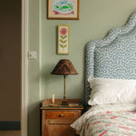 Bedroom with wooden nightstand, lamp, and floral headboard.