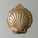 Decorative gold shell-shaped object on a gray background