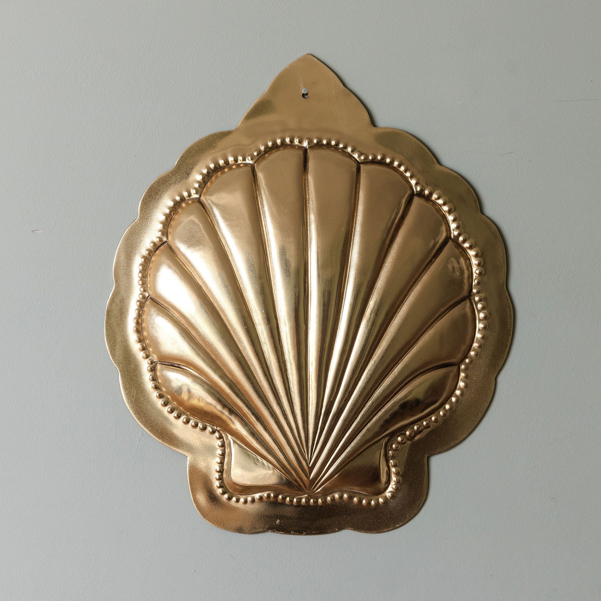 Decorative gold shell-shaped object on a gray background