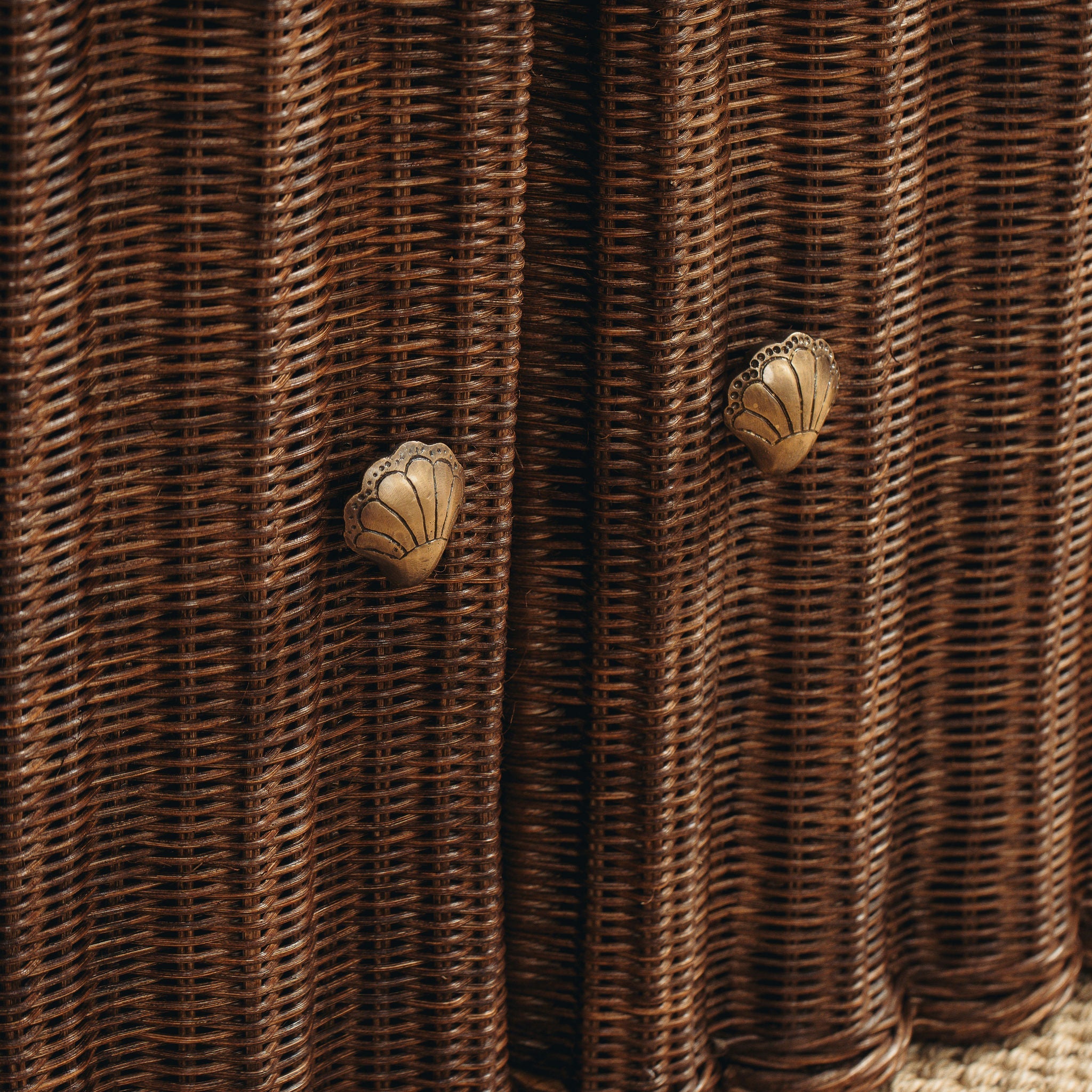 Close-up of woven brown material with butterfly-shaped metal decorations.