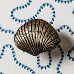 Bronze shell-shaped object on a white background with blue decorative elements