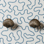 Bronze shell-shaped earrings on a white background with blue shell patterns