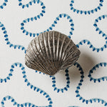 Silver shell-shaped object on a white background with blue decorative elements