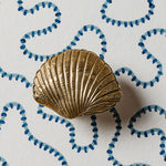 Gold shell-shaped object on a white background with blue decorative elements