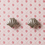 Silver shell-shaped knob on a pink floral patterned background
