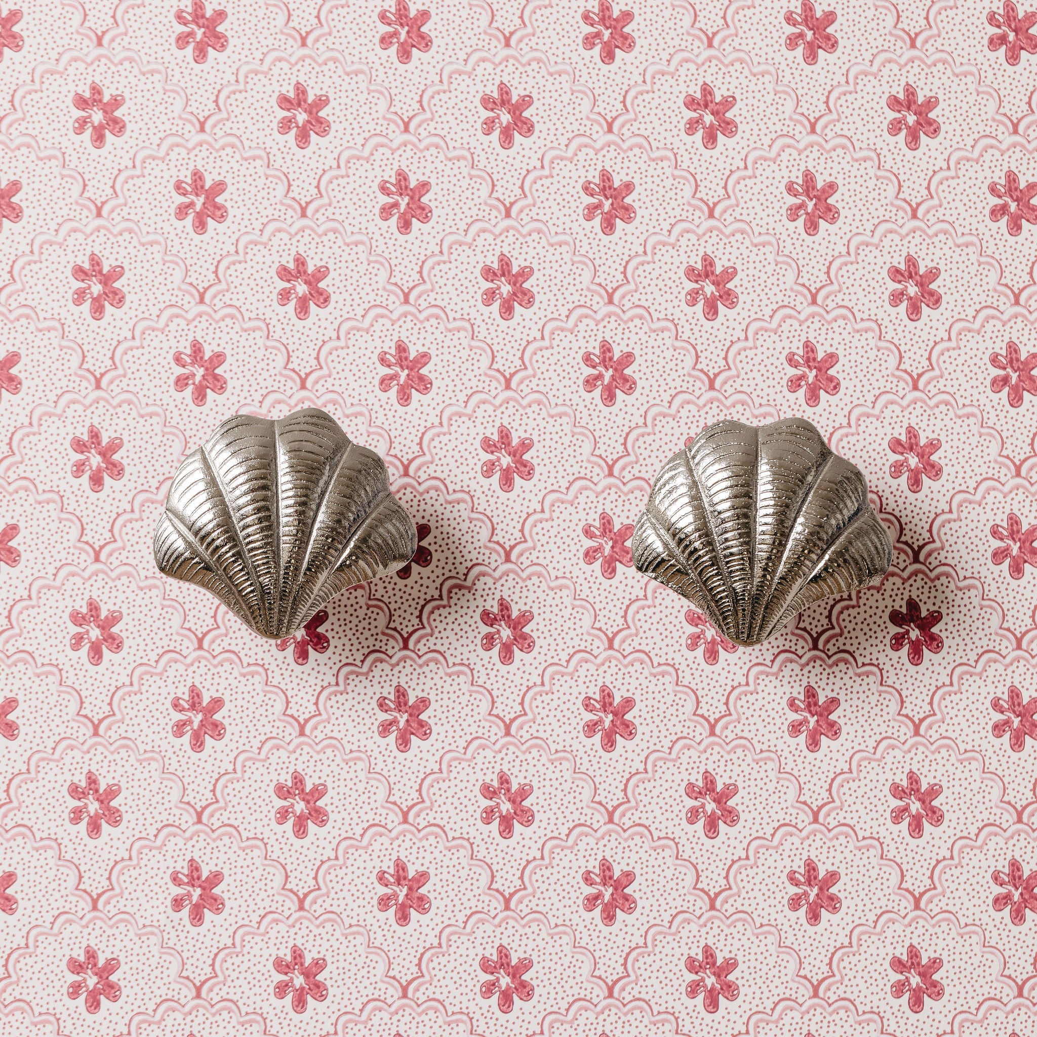 Silver shell-shaped knob on a pink floral patterned background