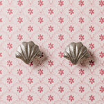 Silver shell-shaped knob on a pink floral patterned background
