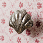 Metallic shell-shaped knob on a floral-patterned background