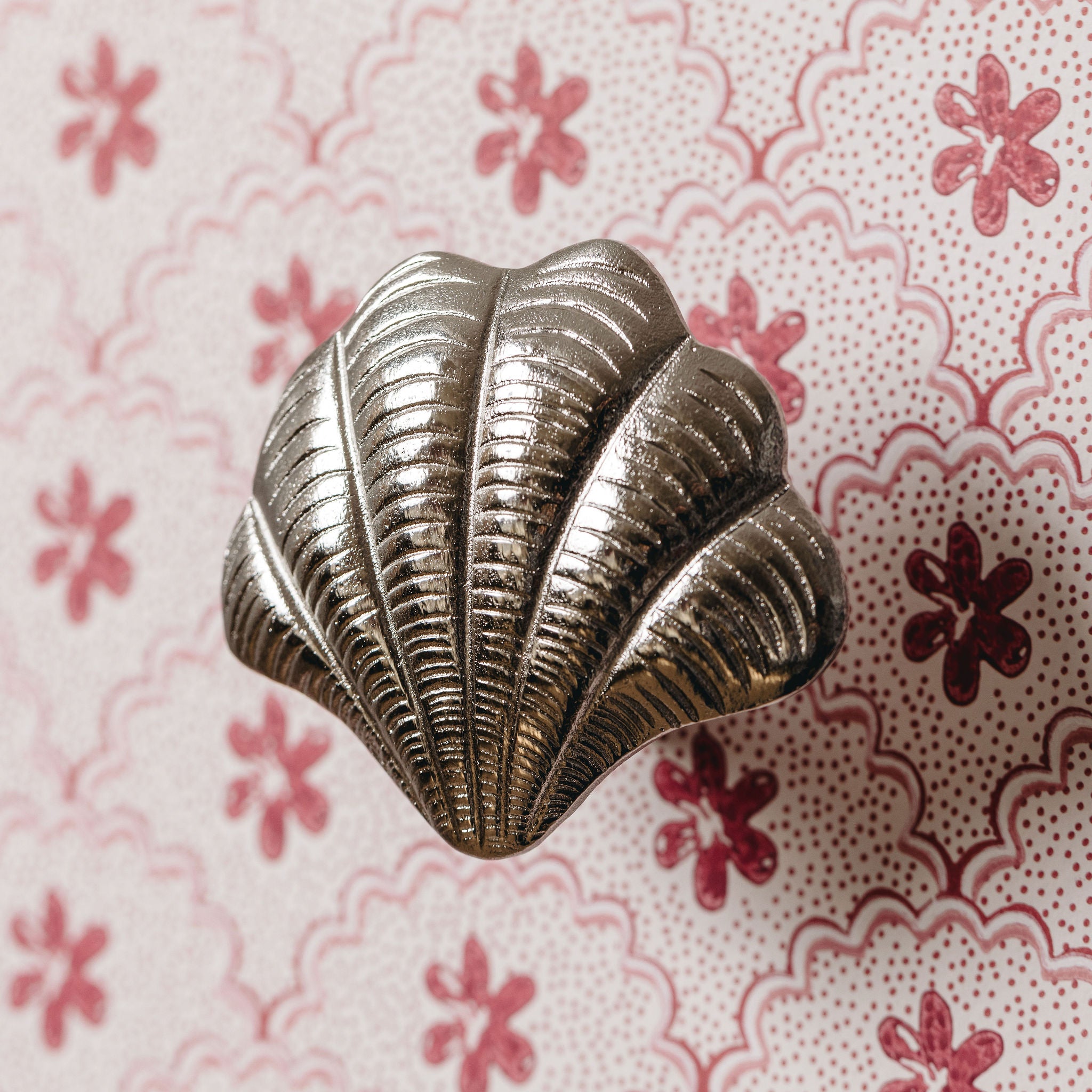 Metallic shell-shaped knob on a floral-patterned background
