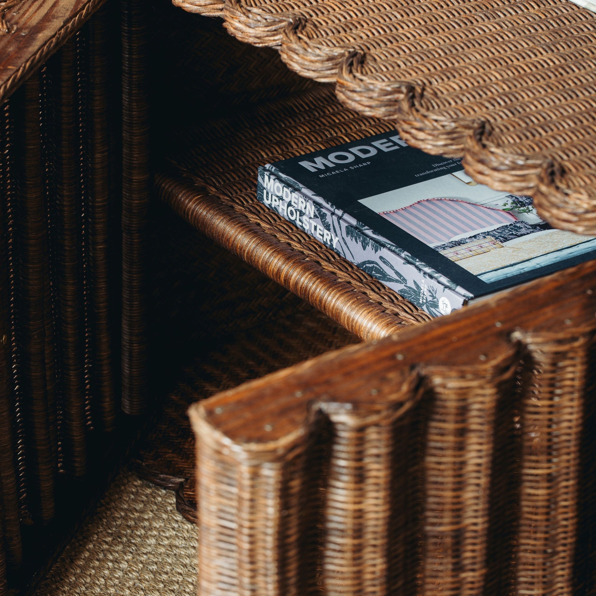 Wicker shelf with a book titled 'Modern Upholstery' on a textured surface