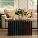 Living room with a beige sofa, Daisy wicker coffee table, and floral arrangement.