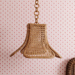 Daphne rattan Woven pendant light hanging against a patterned wall.