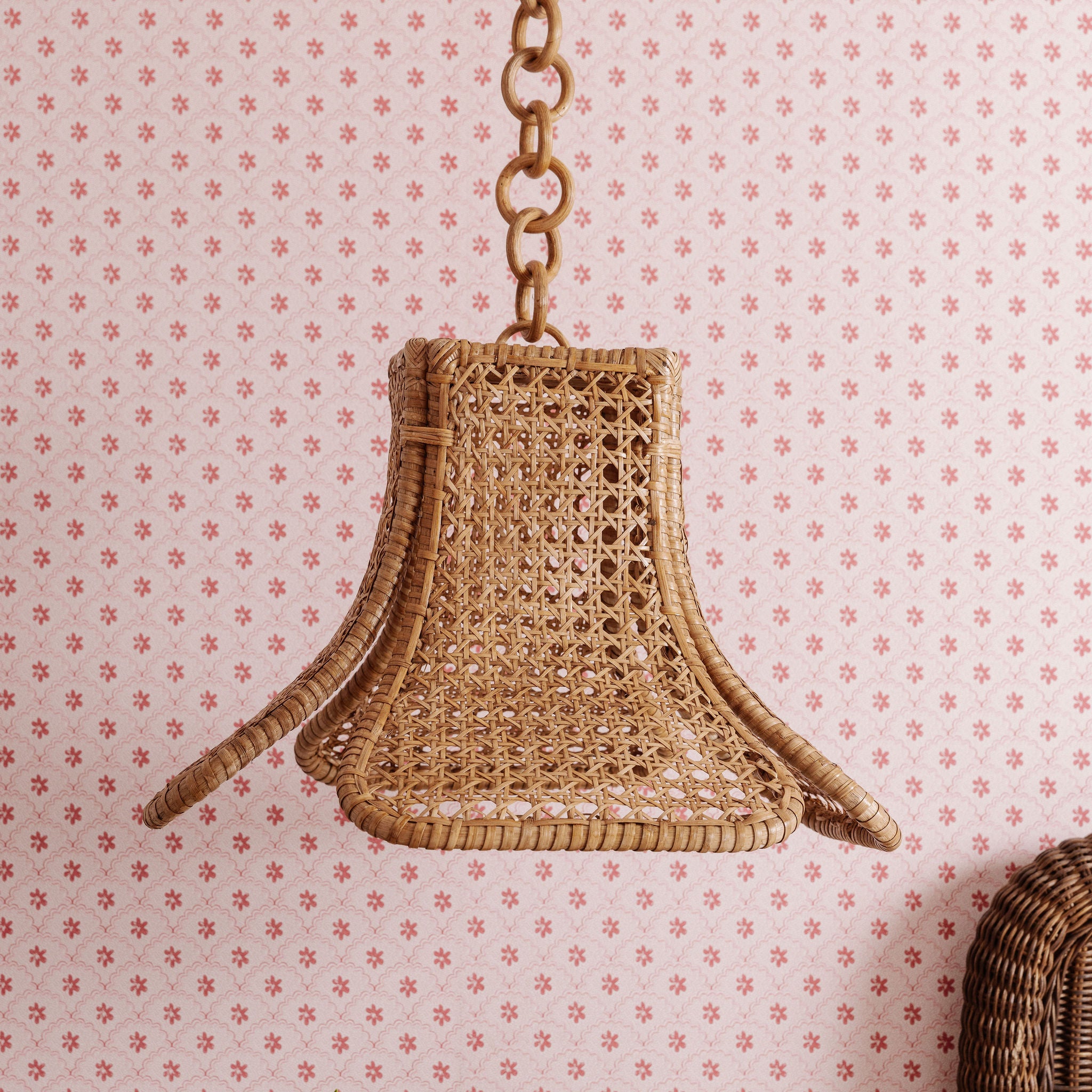 Daphne rattan Woven pendant light hanging against a patterned wall.