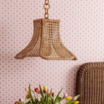 Daphne Woven pendant light fixture on a wall with floral wallpaper and a wicker head board