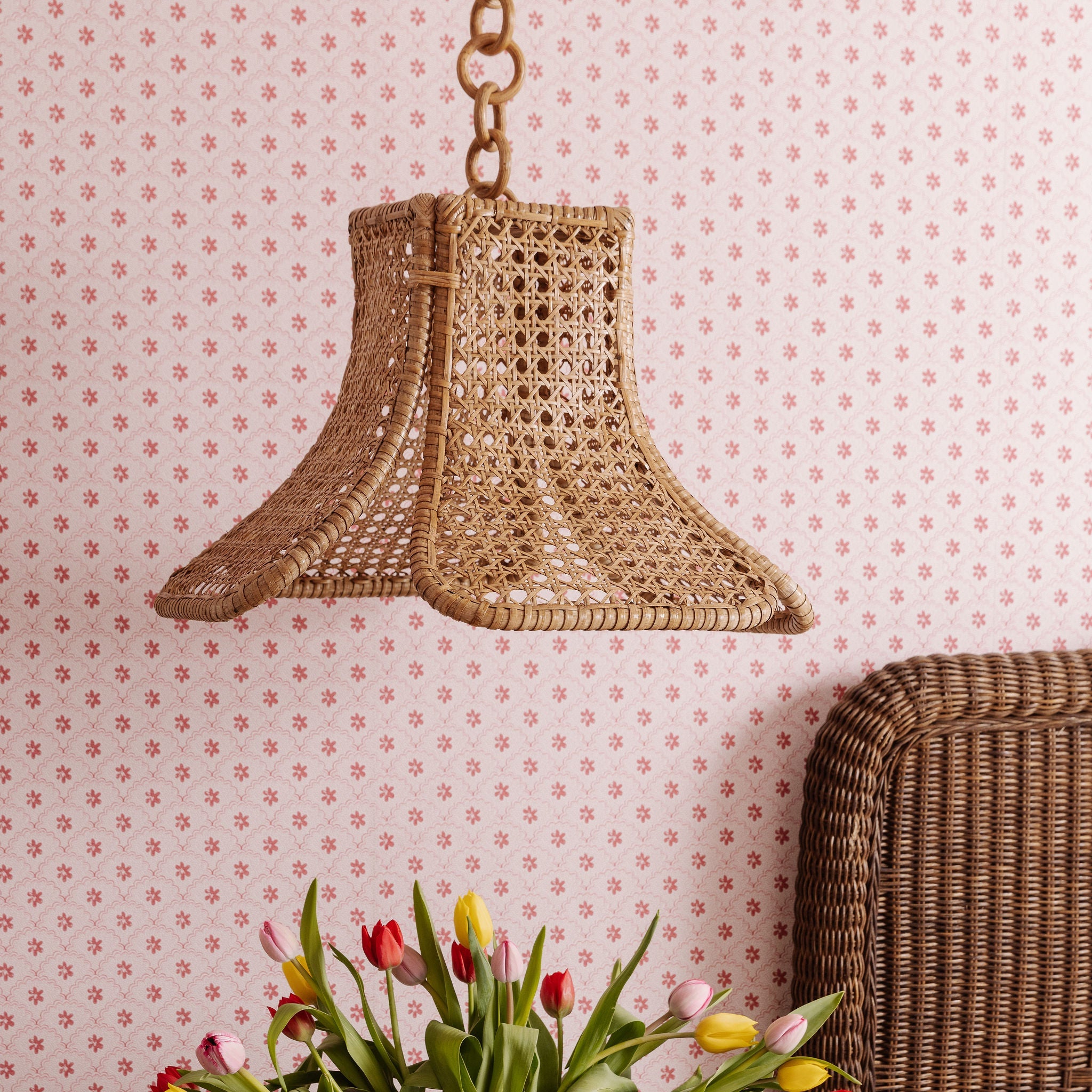Daphne Woven pendant light fixture on a wall with floral wallpaper and a wicker head board