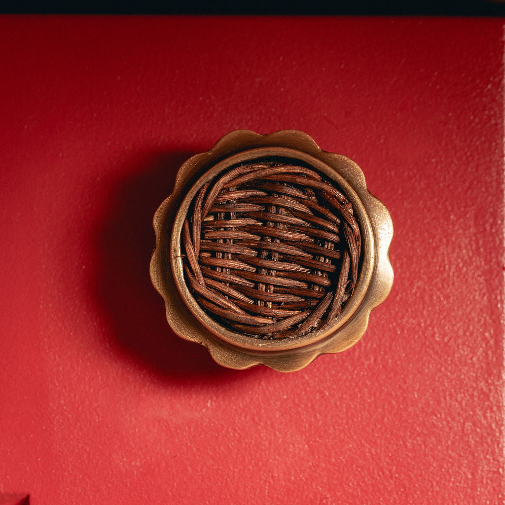 Delilah Round Knob Teak, Aged Brass close up on red