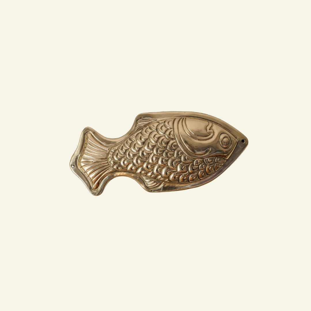 Bronze fish-shaped object on a beige background