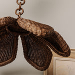 flaral wicker lampshade hanging from a chain against a neutral background