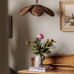 Floral arrangement in a vase on a wooden surface with a shell-shaped lamp and framed picture in the background.