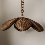 Floral wicker shell-shaped pendant light with chain on a neutral background