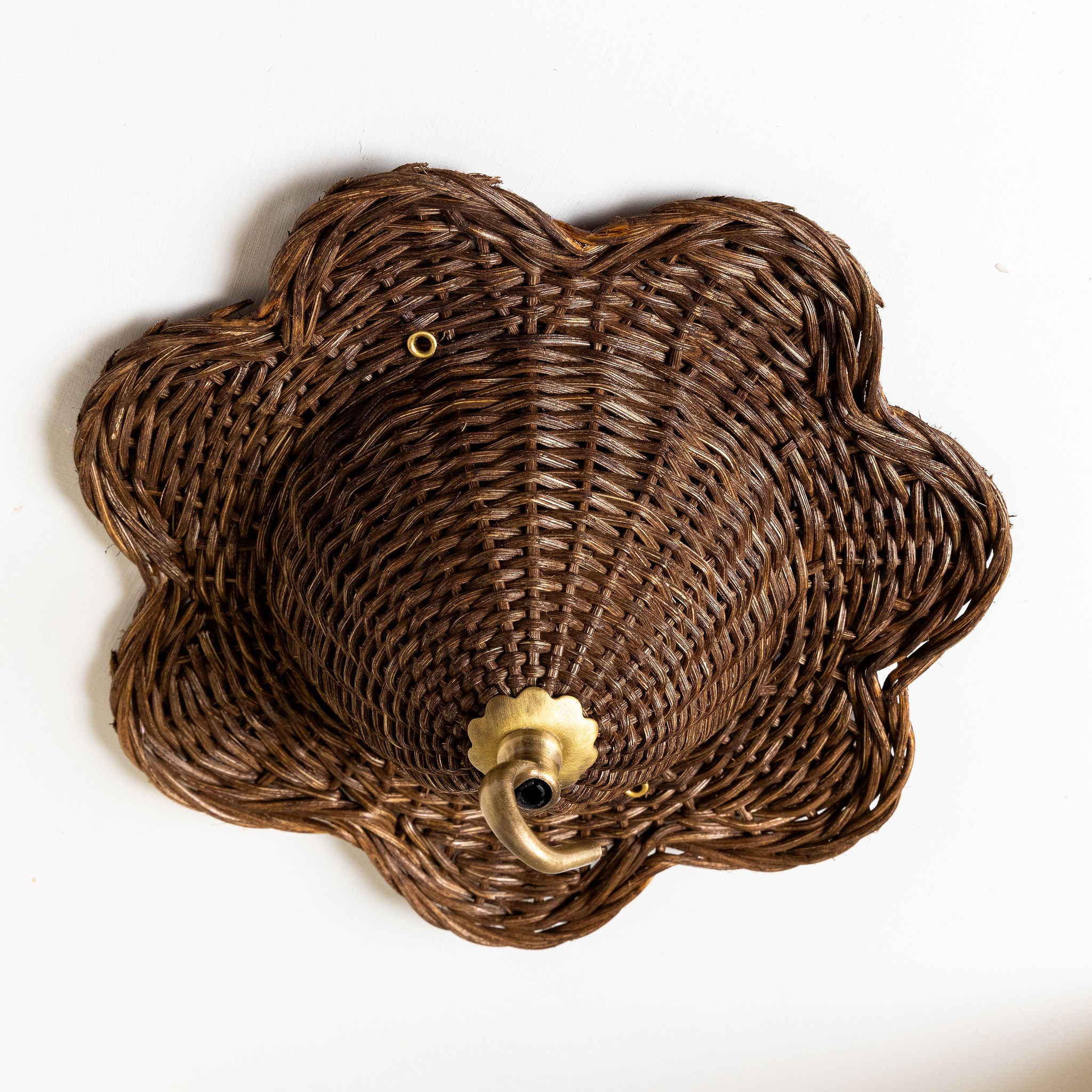 Wicker wall basket with a decorative metal fixture on a white background