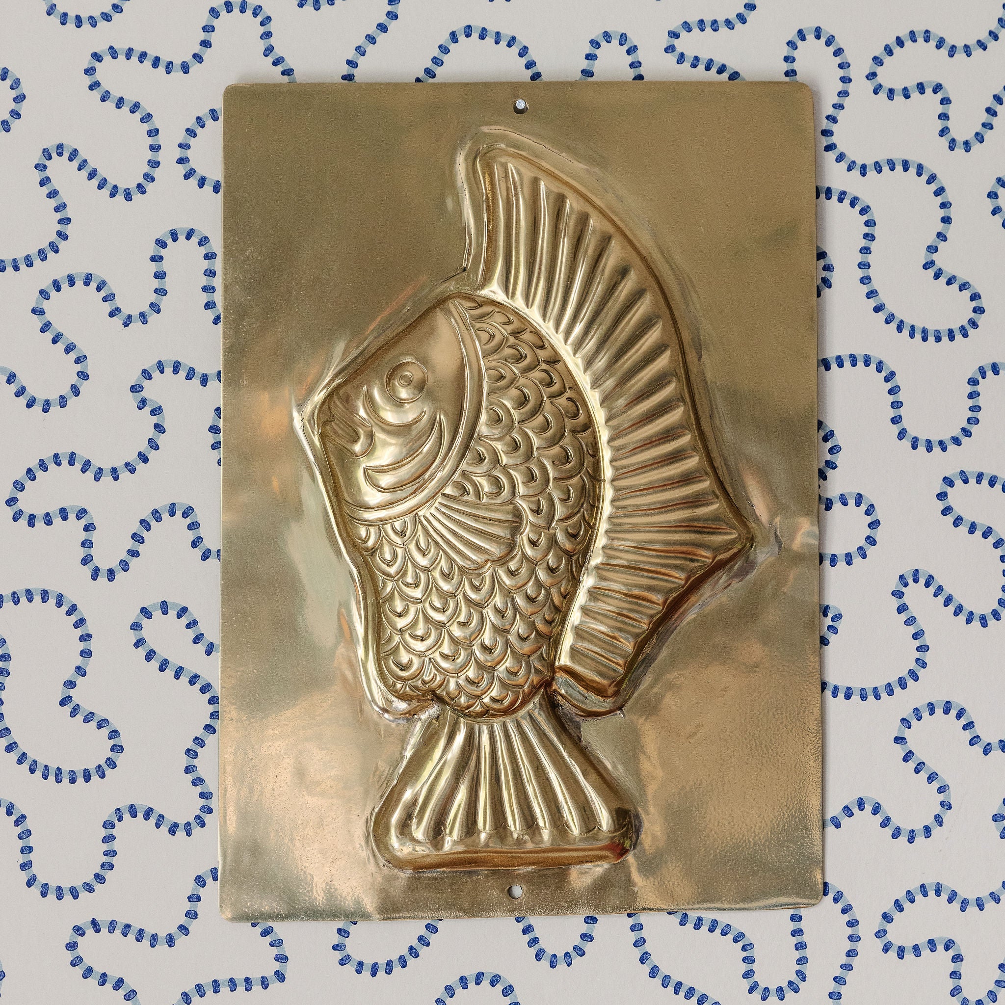 Gold fish-shaped mold on a textured blue and white background