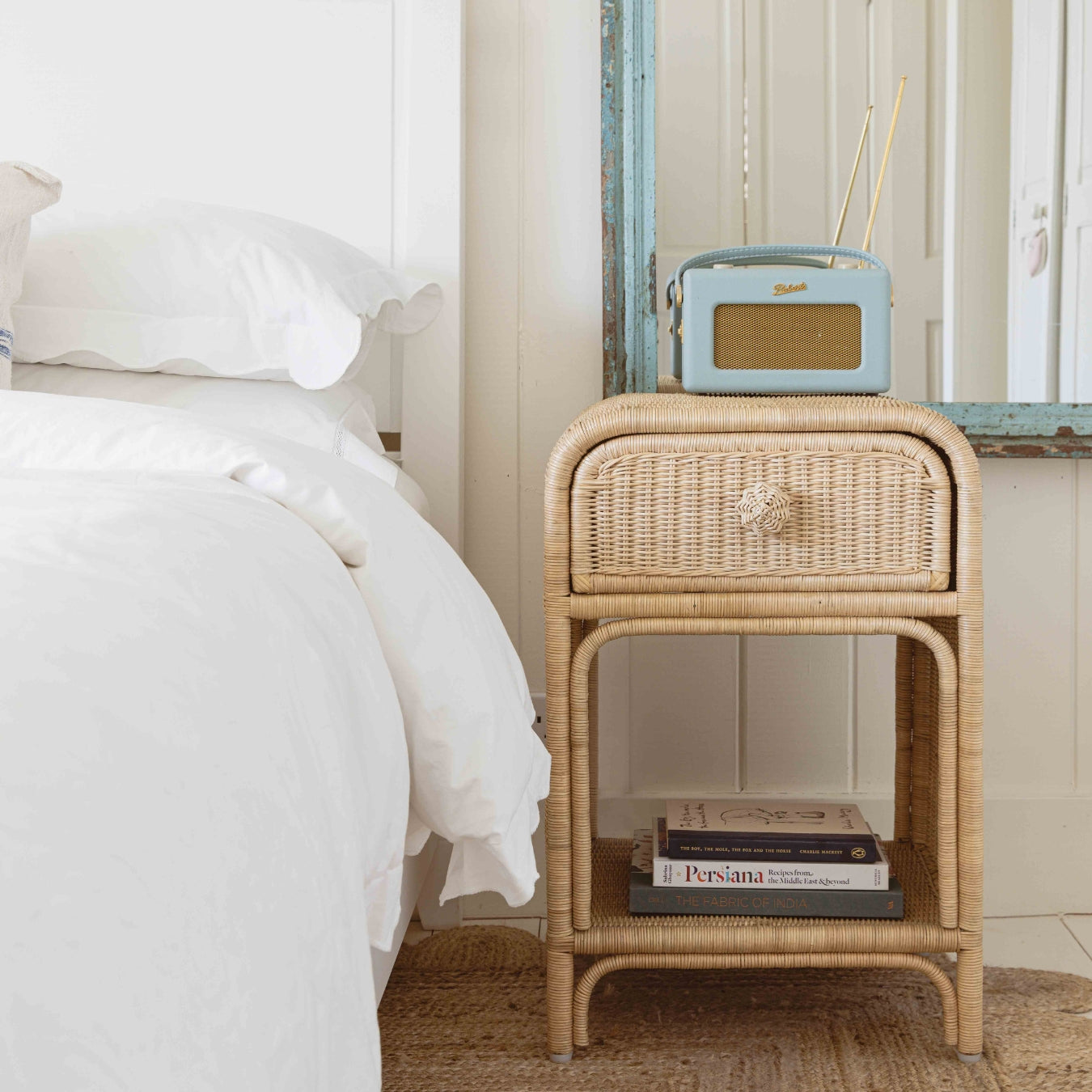 phoenix wicker nightstand next to a bed with a radio and books on top