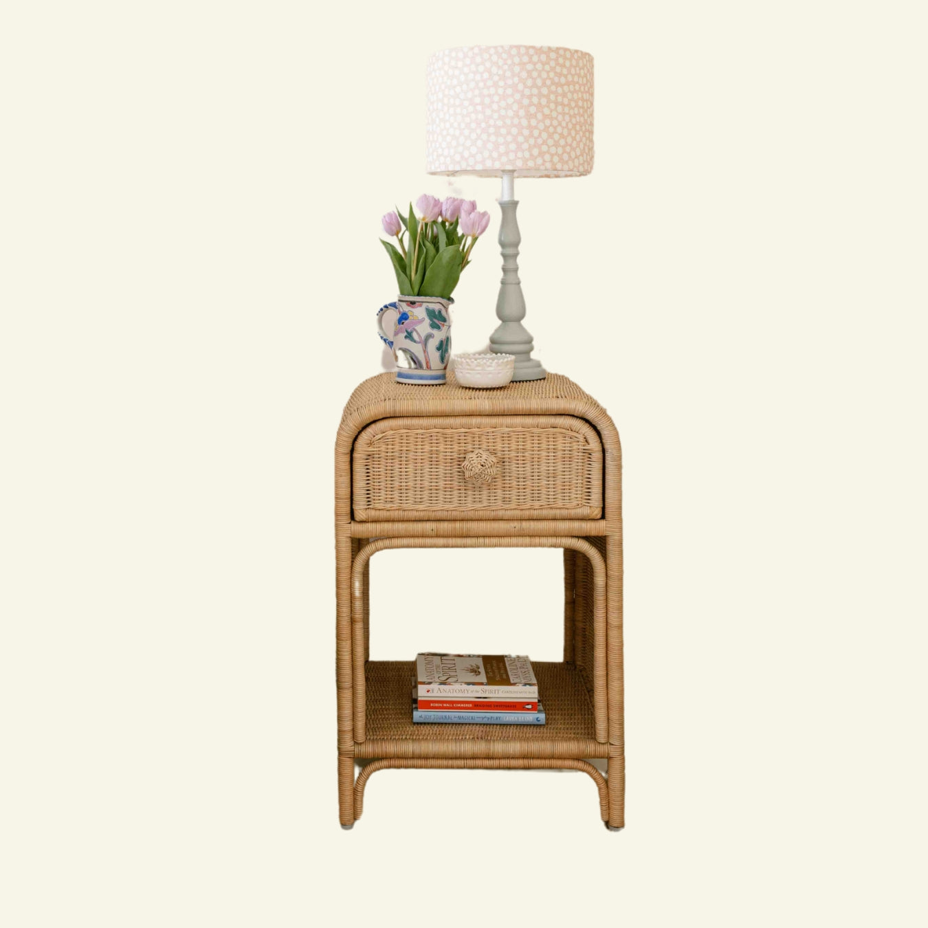 Phoenix Wicker side table with lamp, flowers, and books on a white background