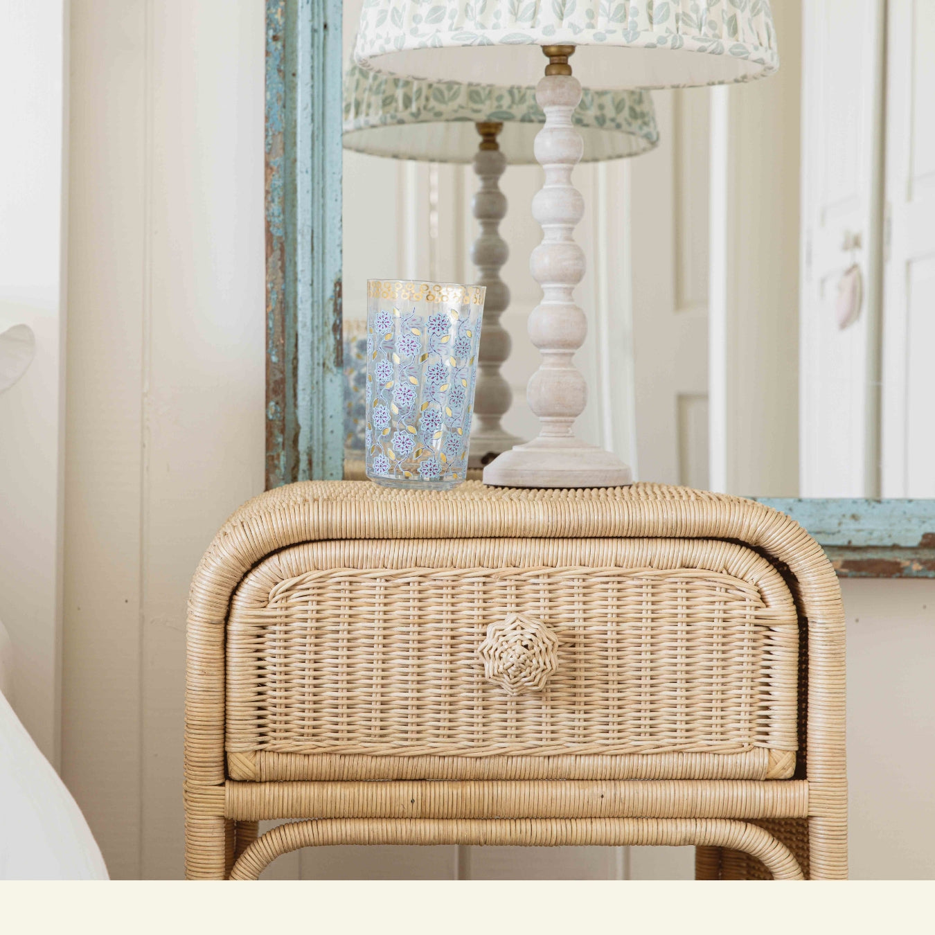 Wicker nightstand with lamp and decorative item in a room setting