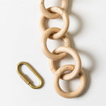 Wooden chain with a brass carabiner on a white background
