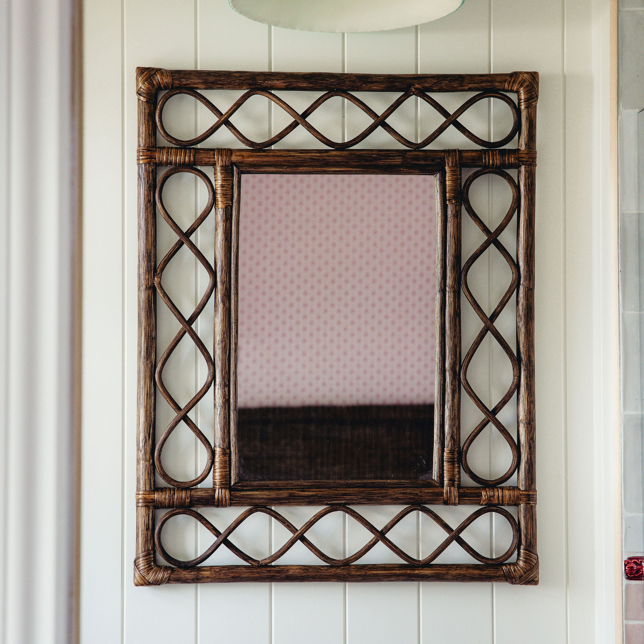 Retro-rattan-mirror-teak-on-a-white-wall-close-up
