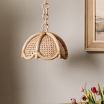 Riviera woven pendant light fixture on a neutral wall with flowers and a painting.