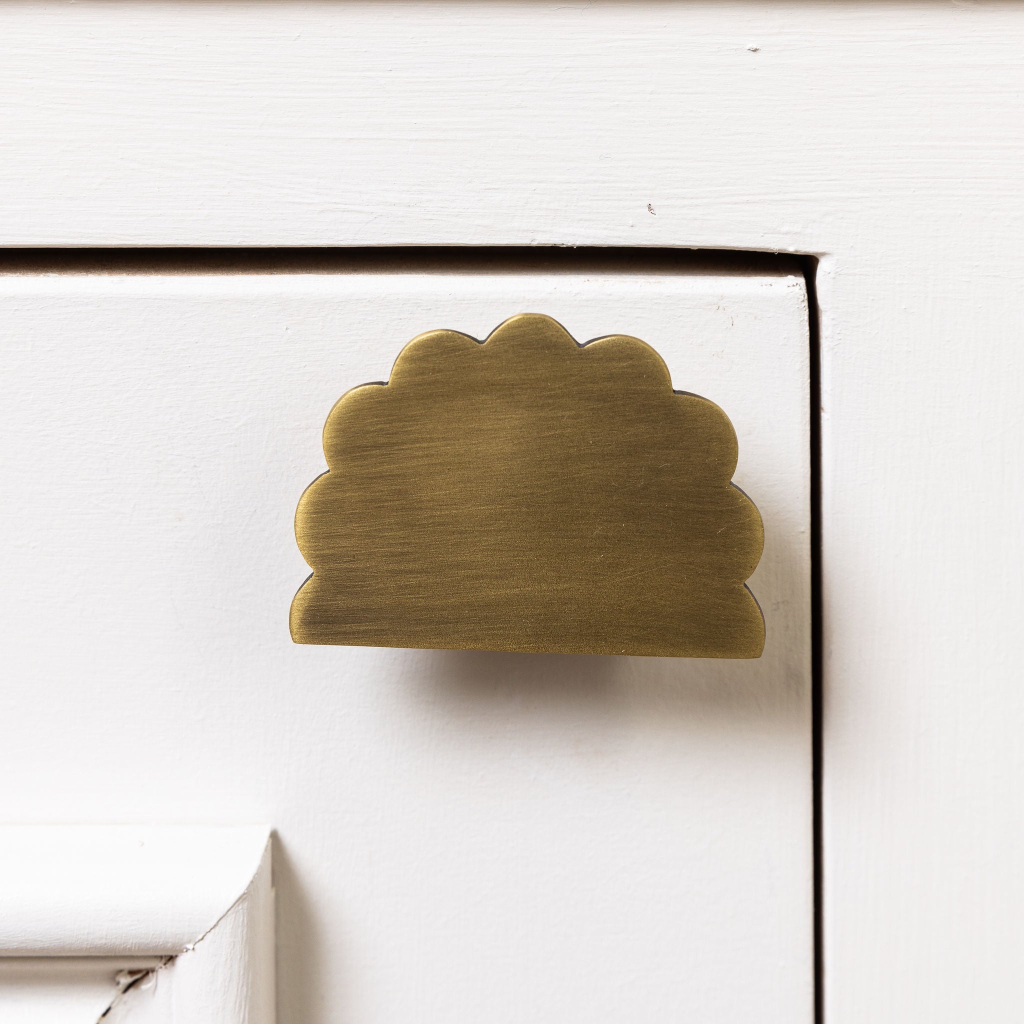 Brass cloud-shaped handle on a white cabinet