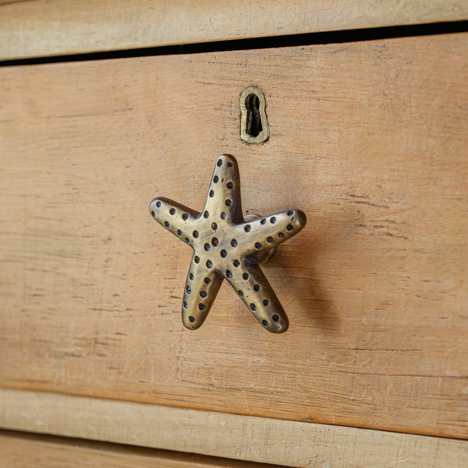 Brass starfish-shaped handle on a wooden surface