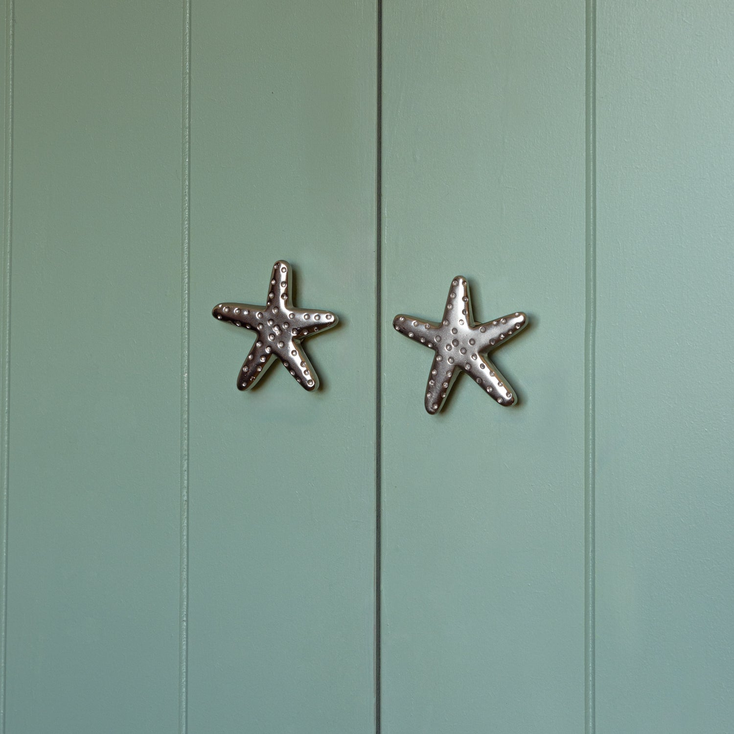 Starfish-shaped cabinet knobs on a light green wooden door