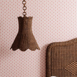Calla Wicker lampshade hanging against a patterned wall.