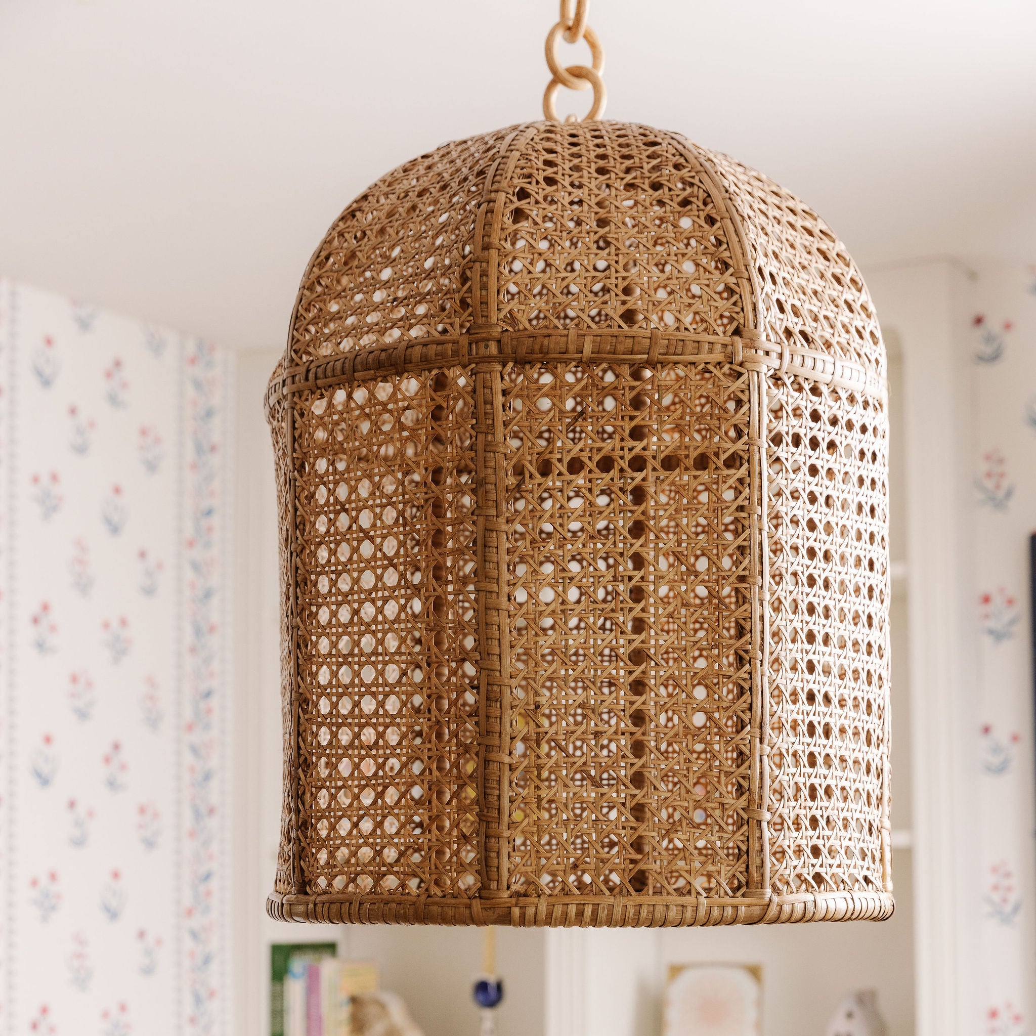 Violet woven rattan pendant light hanging against a neutral background