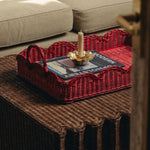Red wicker tray with a candle and books on a textured surface, blurred background