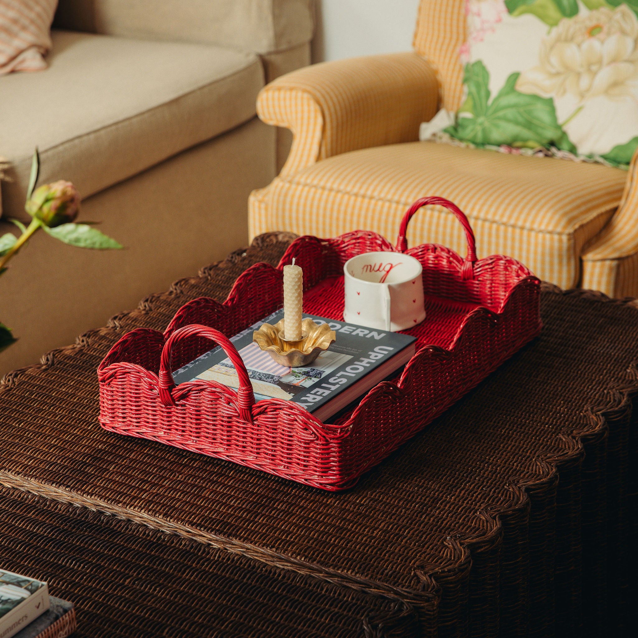 Red wicker tray with a magazine and candle on a dark surface in a living room setting.
